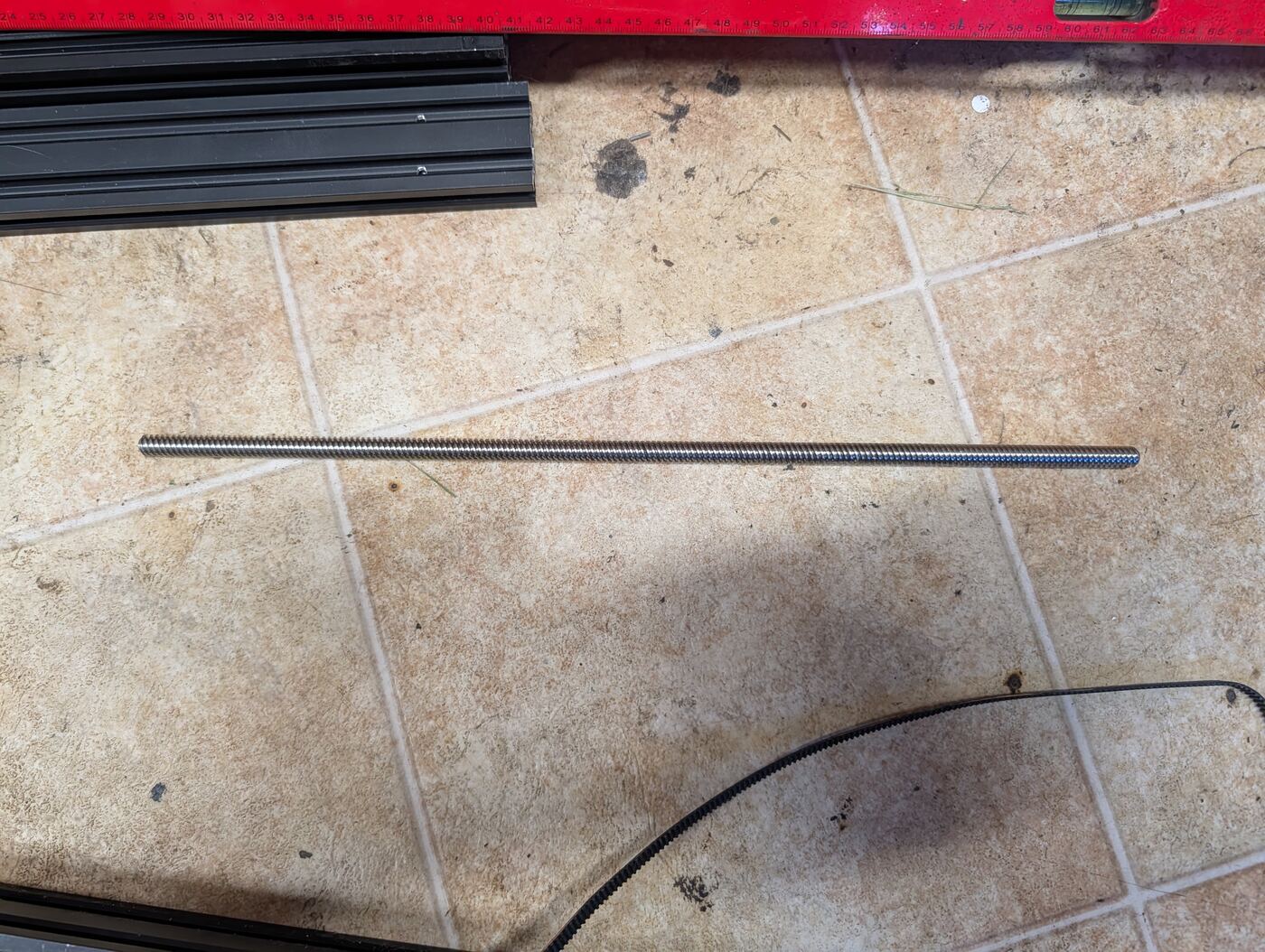 A length of threaded steel rod stock next to V-slot rail and a belt