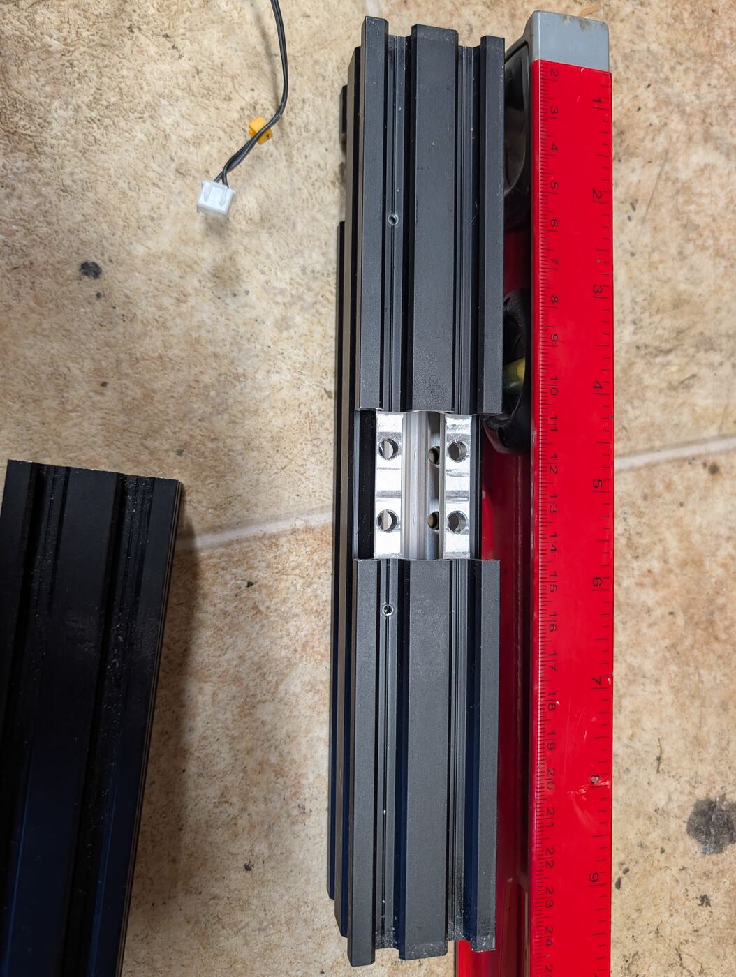 Two V-slot aluminum rails joined together with an internal connector plate, measured with a ruler